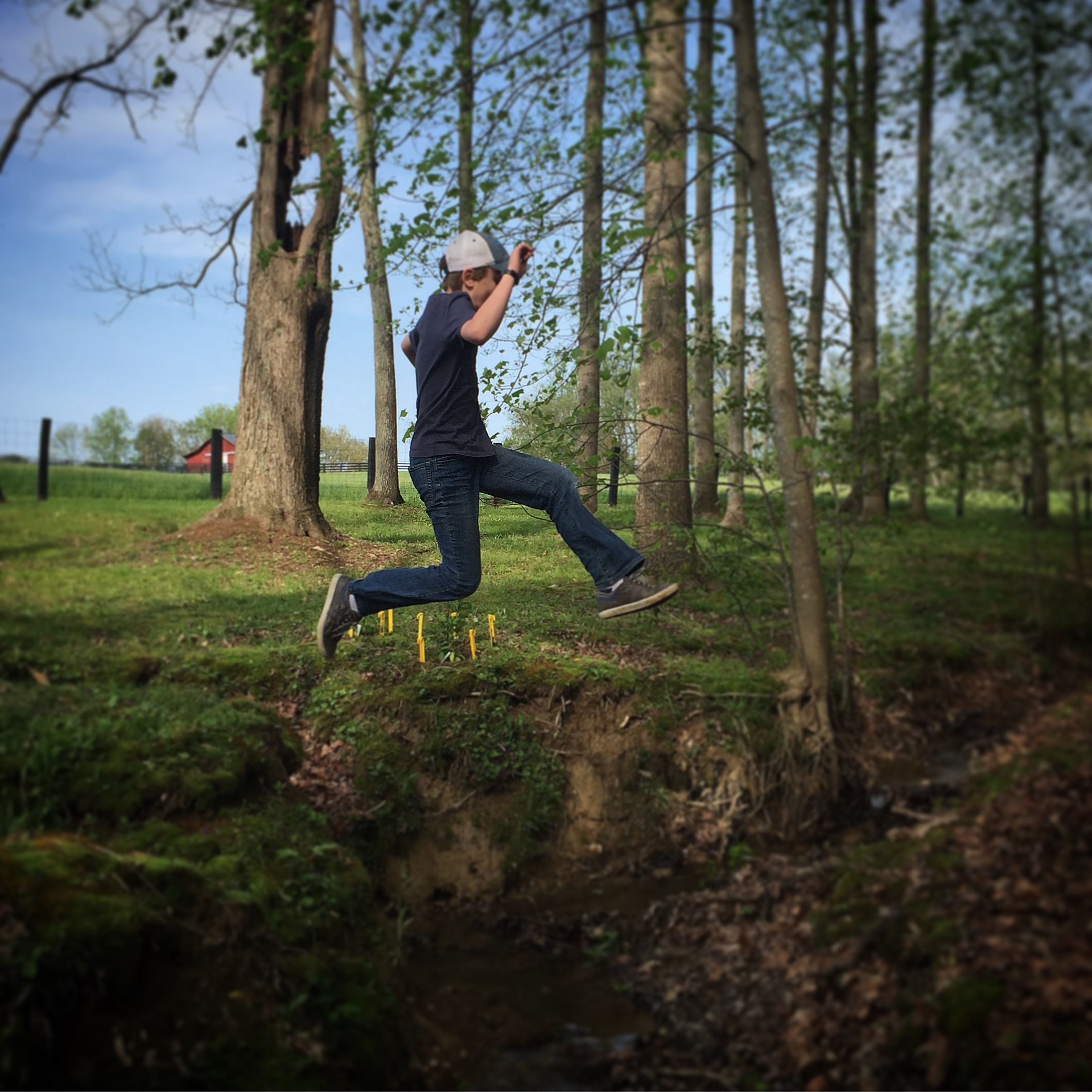 Boy jumping over a creek.