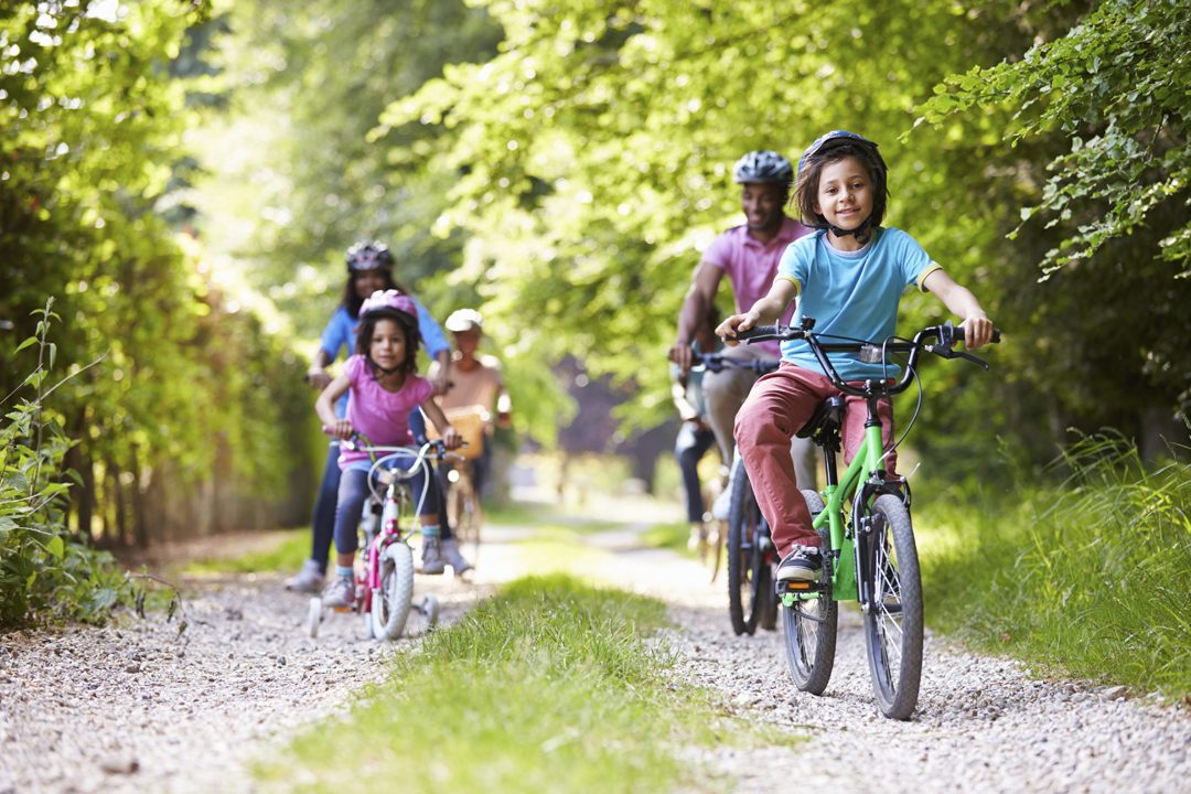 A happy, healthy family bikes on a dirt road.