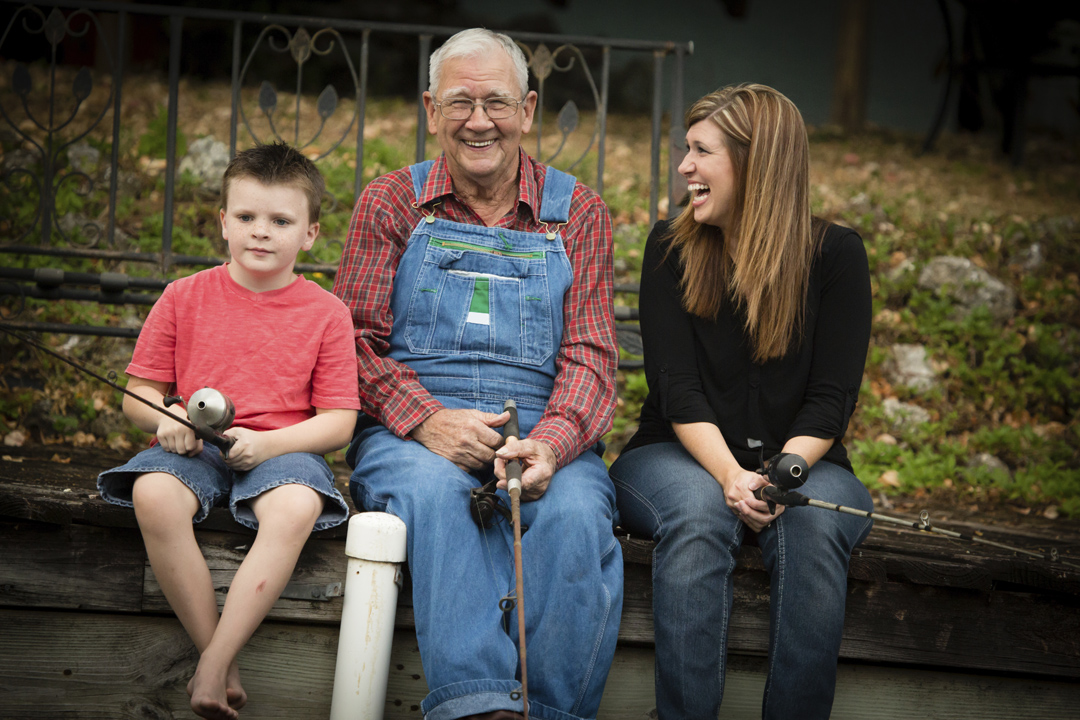 Three generations of a happy family. Smiling grandfather is sitting in between his grandson and his daughter, who is laughing.